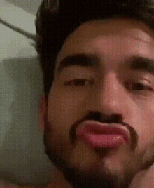 a man with a beard is making a face with his tongue out