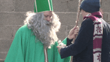 a man in a green robe with a scarf that says ' a ' on it
