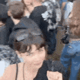 a woman wearing sunglasses is standing in a crowd of people at a concert .