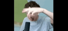 a man is sitting in front of a microphone making a funny face .