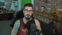 a man wearing glasses and a tank top is talking into a microphone