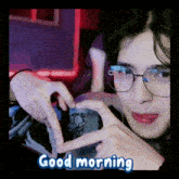 a person wearing glasses is making a heart shape with their fingers and the words good morning are below them