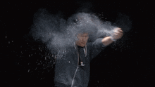 a man in a grey sweatshirt is surrounded by a cloud of dust
