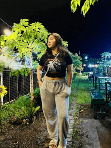 a woman wearing a metallica shirt stands in a garden