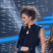 a woman in a black crop top is dancing on a stage with the name lamalucia on the bottom right