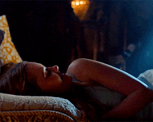 a woman is laying on a bed with her head on a pillow and her eyes closed