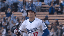 a baseball player wearing a dodgers uniform is standing on the field in front of a crowd .