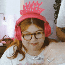 a woman wearing headphones and a pink crown with the word happy birthday on it