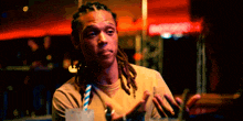 a man with dreadlocks is sitting at a table with a drink