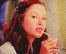 a woman drinking through a straw from a cup with the letters ct on the bottom