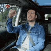 a man in a denim jacket is sitting in the back seat of a car with trt muzik written on the window