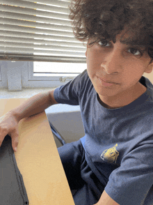 a young boy with curly hair wearing a blue shirt with the letter g on the front