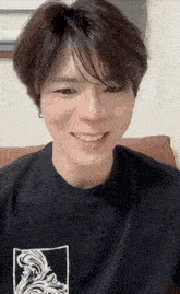 a young man wearing a black t-shirt with a white graphic on it smiles