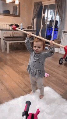a little girl is playing with a wooden stick