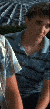 a man in a blue shirt is sitting in front of rows of empty seats