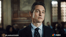 a man in a suit and tie stands in front of a crowd with the hashtag lawandorder