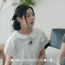 a woman in a white shirt is sitting on a couch with korean writing on the bottom