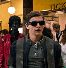 a man wearing sunglasses is standing in front of a sign that says tick