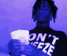 a man wearing a shirt that says " on ' t ice2e " is holding some cards