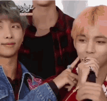 a group of young men are sitting next to each other and one of them is holding a microphone .