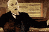 a man in a tuxedo and bow tie stands in front of an organ