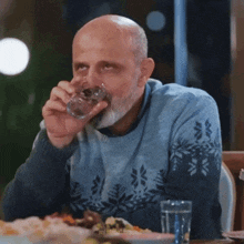 a bald man with a beard is sitting at a table eating food