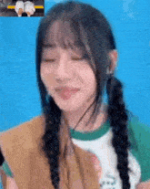 a close up of a girl with pigtails making a funny face with her eyes closed .