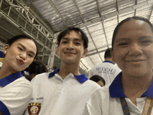 a man and two women pose for a picture with a man wearing a shirt that says muxcrm on it
