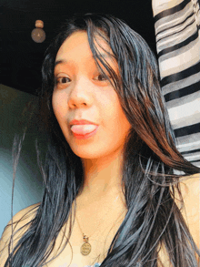 a woman wearing a necklace with a pendant that says ' jesus ' sticking her tongue out