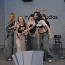 a group of young women are dancing in front of a sign that says denti studios