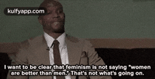 a man in a suit and tie is talking about feminism and women are better than men .