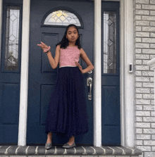 a young girl in a blue dress stands in front of a blue door