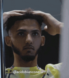 a man with a beard is looking at himself in a mirror with the hashtag @acidobianconero