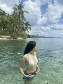 a woman in a bikini stands in a body of water