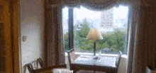 a table and chairs in front of a window with a lamp