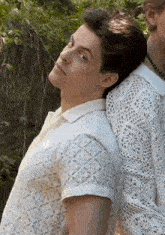 a man in a white shirt is standing next to another man in a white lace shirt