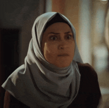 a woman wearing a hijab looks surprised and shocked