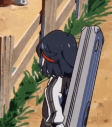 a cartoon girl is standing next to a wooden fence holding a gun .