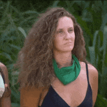a woman with curly hair and a green scarf around her neck is smiling .