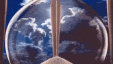 a hourglass with a blue sky and clouds behind it