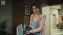 a woman in a pink jacket is standing in a hallway with #buson olsun on the bottom right