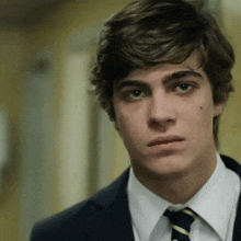 a young man in a suit and tie looks at the camera with a serious look on his face