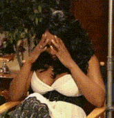 a woman sitting in a chair with her hands on her face