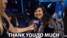 a woman is holding a microphone and saying thank you so much .