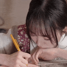 a woman is writing on a piece of paper with a yellow pen in her hand