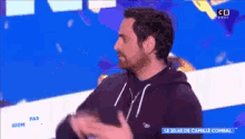 a man in a black hoodie is on a television screen