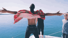 a shirtless man with his arms outstretched is standing on a boat