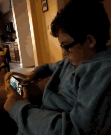 a young boy wearing glasses is playing a game on a cell phone