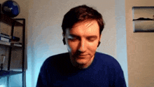a man wearing a blue shirt is standing in front of a globe
