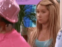 a woman in a pink hat is standing next to another woman in a blue shirt .